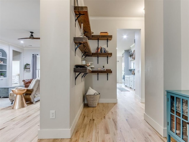 hall with baseboards, ornamental molding, and light wood-type flooring