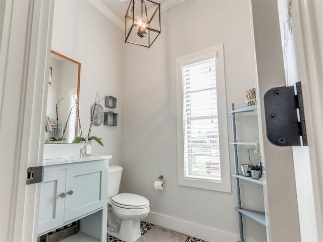 half bathroom featuring crown molding, a notable chandelier, vanity, toilet, and baseboards
