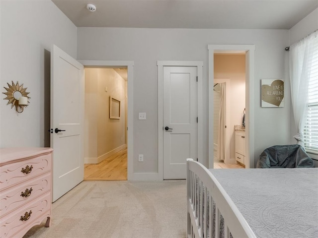 bedroom with light colored carpet, baseboards, and ensuite bathroom