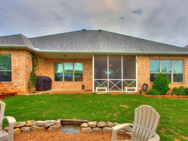 rear view of property featuring brick siding, roof with shingles, and a yard
