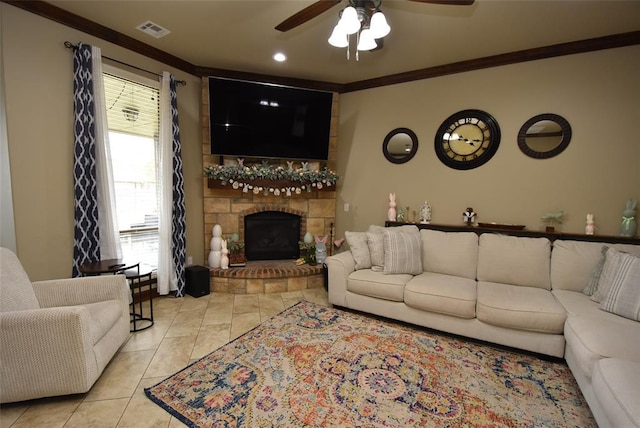 living area with visible vents, light tile patterned floors, ornamental molding, ceiling fan, and a stone fireplace