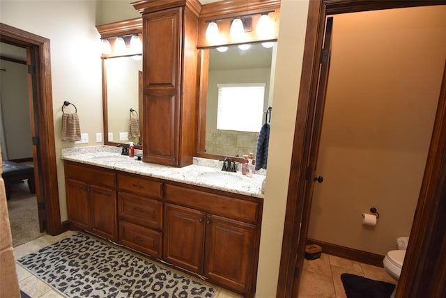 bathroom with tile patterned flooring, double vanity, a sink, and toilet