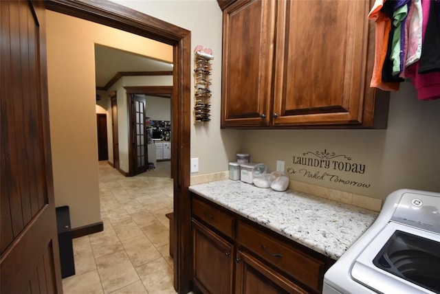 laundry room with light tile patterned floors, arched walkways, ornamental molding, cabinet space, and washer / dryer