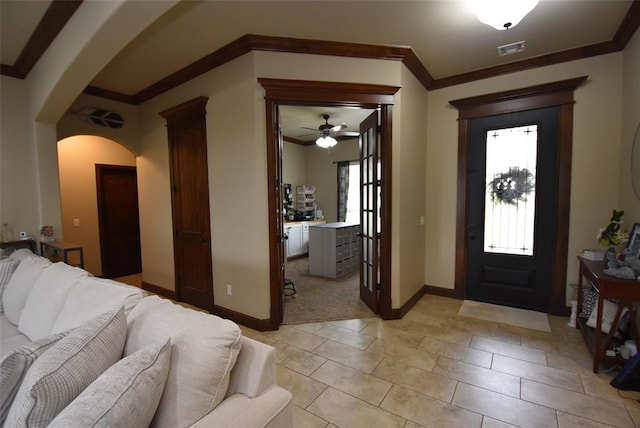 foyer featuring arched walkways, ceiling fan, ornamental molding, and visible vents