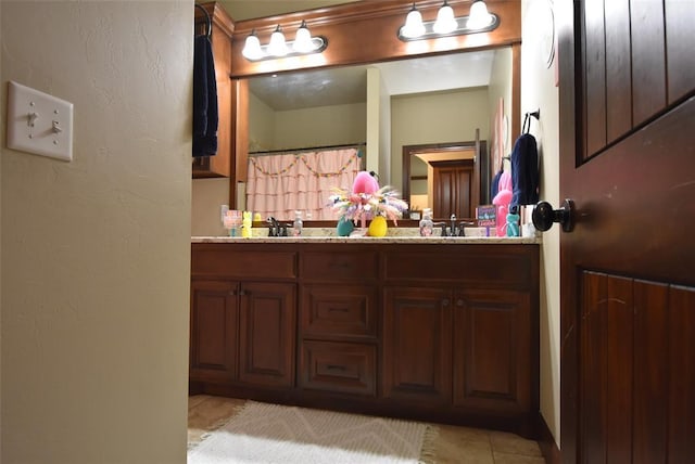 bathroom with a sink, tile patterned floors, double vanity, and a textured wall