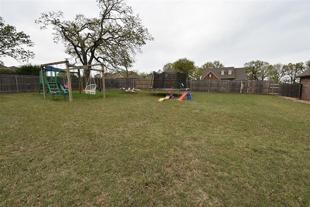 view of yard with a trampoline, a fenced backyard, and a playground