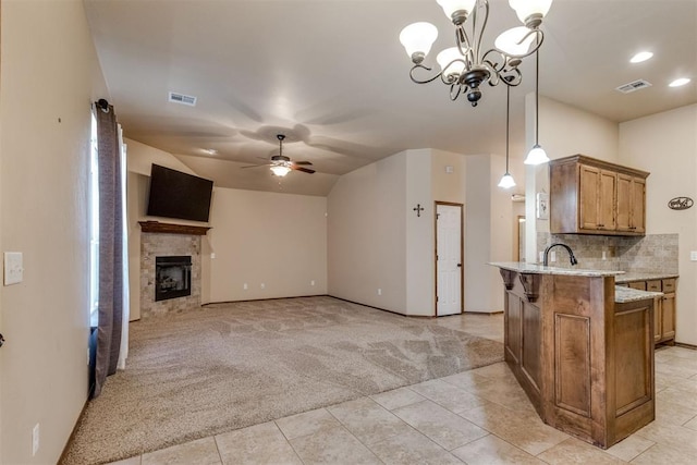 3719 Black Forrest Ct, Newcastle, OK 73065 - kitchen featuring ceiling fan with notable chandelier, brown cabinetry, light carpet, light stone counters, and light tile patterned flooring