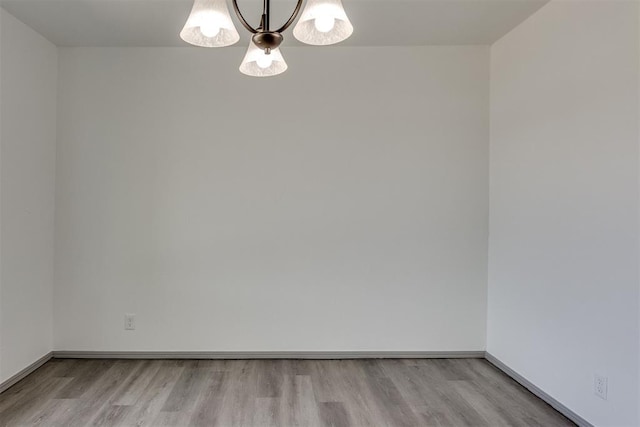 2621 NW 121st St, Oklahoma City, OK 73120 - unfurnished room featuring wood finished floors, baseboards, and an inviting chandelier