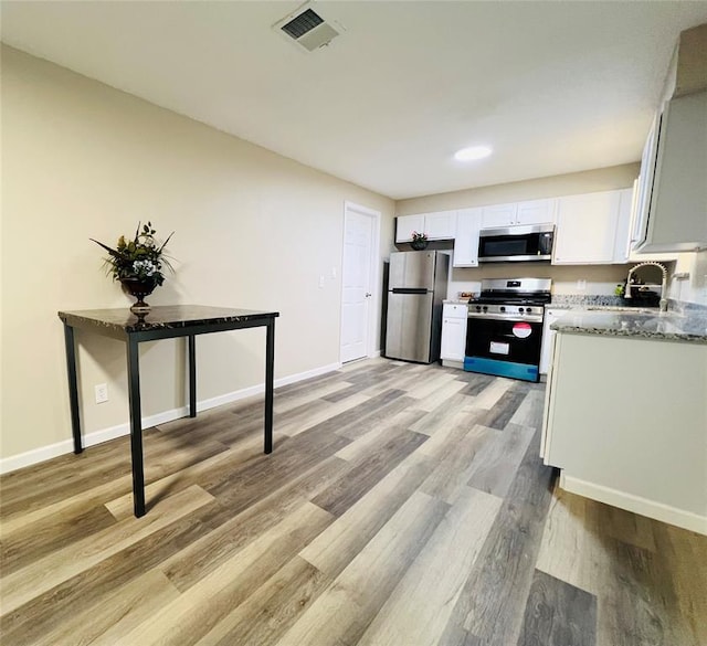kitchen featuring light wood-style flooring, white cabinetry, visible vents, appliances with stainless steel finishes, and a sink