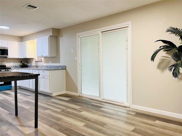 kitchen with baseboards, white cabinets, visible vents, stainless steel appliances, and light wood finished floors