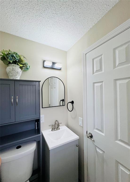 bathroom featuring toilet, vanity, and a textured ceiling