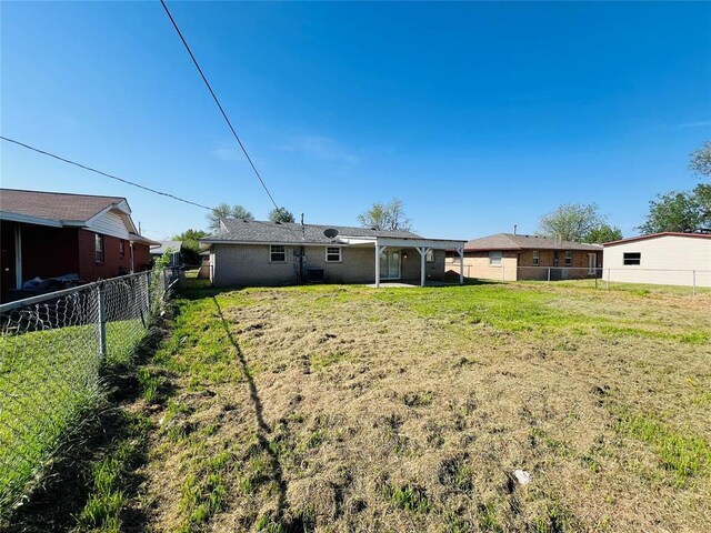 rear view of property with a yard and a fenced backyard
