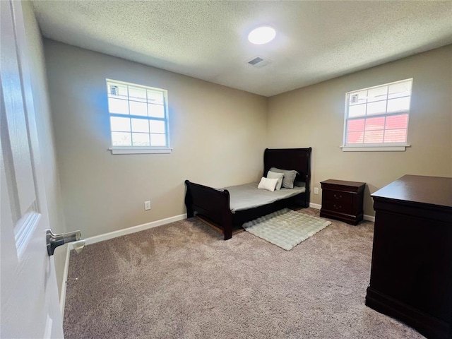 bedroom featuring carpet floors, a textured ceiling, visible vents, and baseboards