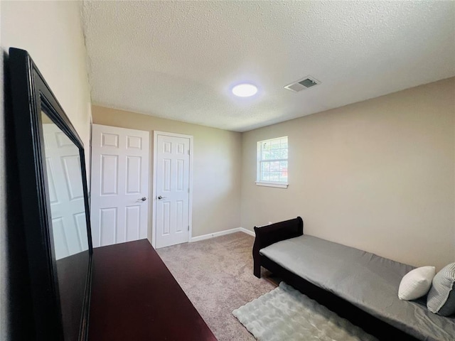 carpeted bedroom with baseboards, visible vents, and a textured ceiling