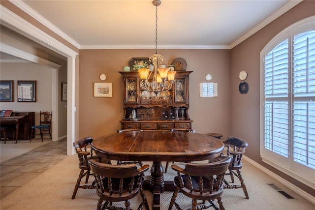 dining area with baseboards, visible vents, a chandelier, and crown molding
