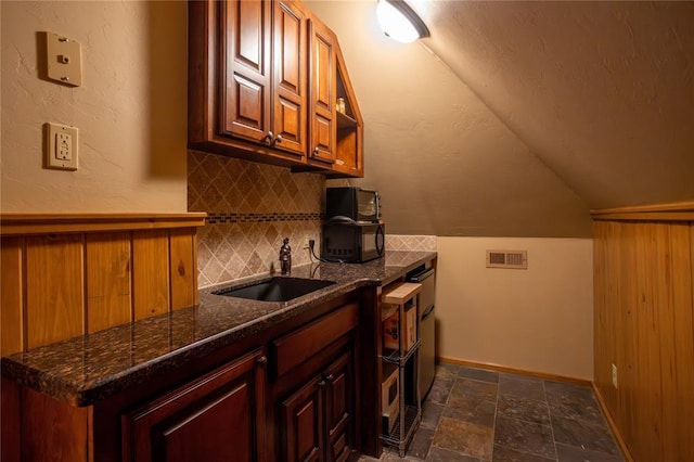 interior space featuring a sink, tasteful backsplash, vaulted ceiling, visible vents, and stone finish floor