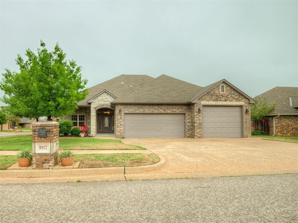 9117 NW 92nd St, Yukon, OK 73099 - view of front facade with concrete driveway, brick siding, a shingled roof, and a garage