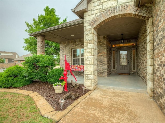 property entrance with stone siding, a porch, and brick siding