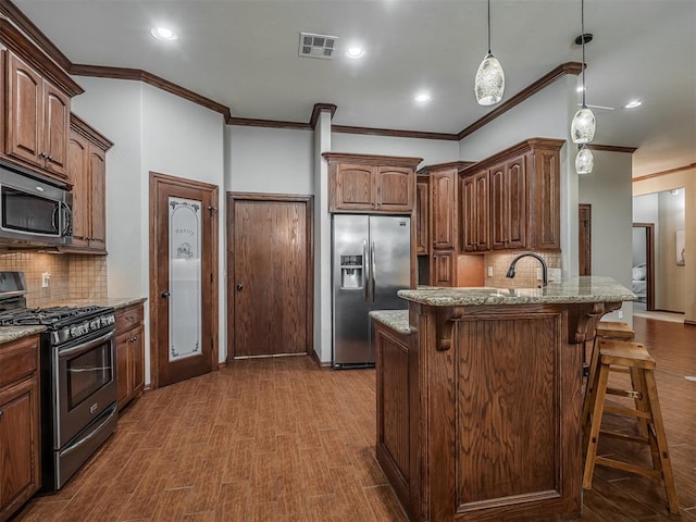 kitchen with crown molding, a breakfast bar, stainless steel appliances, tasteful backsplash, and visible vents