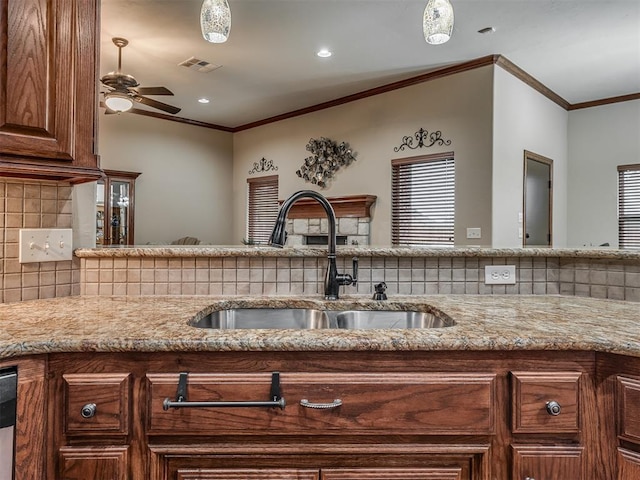 kitchen featuring light stone counters, a sink, a ceiling fan, backsplash, and visible vents