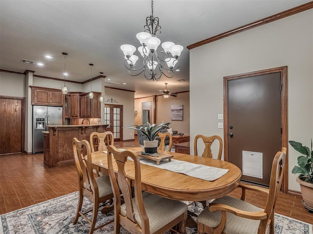 dining room featuring visible vents, ornamental molding, wood finished floors, and ceiling fan with notable chandelier