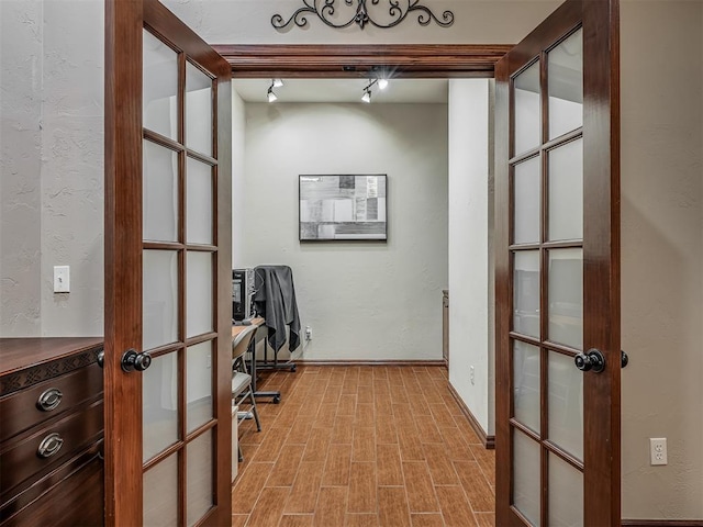 office area with french doors, baseboards, a textured wall, and light wood-type flooring