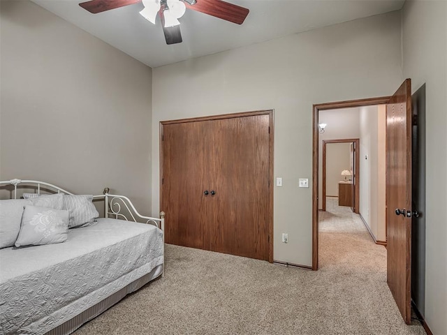 bedroom with a ceiling fan, light carpet, and a closet