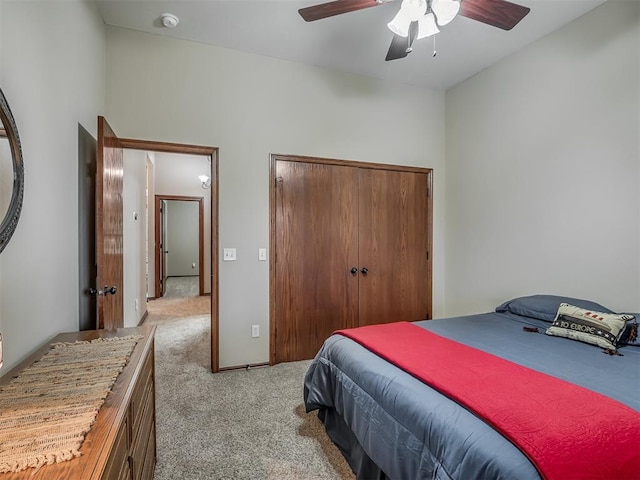 bedroom featuring a ceiling fan, light carpet, and a closet