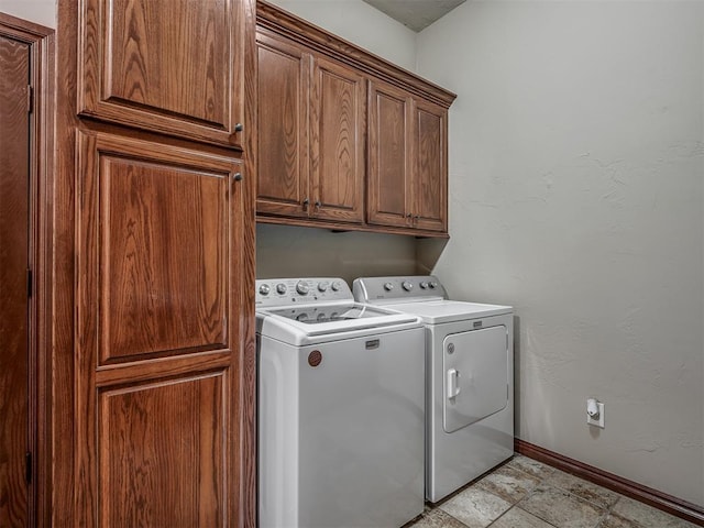 washroom with baseboards, washing machine and dryer, and cabinet space