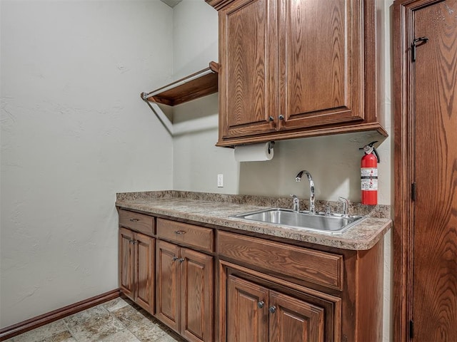 kitchen featuring a sink, baseboards, and brown cabinetry