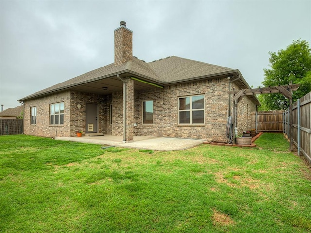 back of house featuring brick siding, a fenced backyard, a chimney, a patio, and a yard