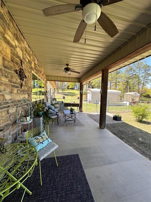 view of patio / terrace featuring an outbuilding, fence, a ceiling fan, and a storage unit