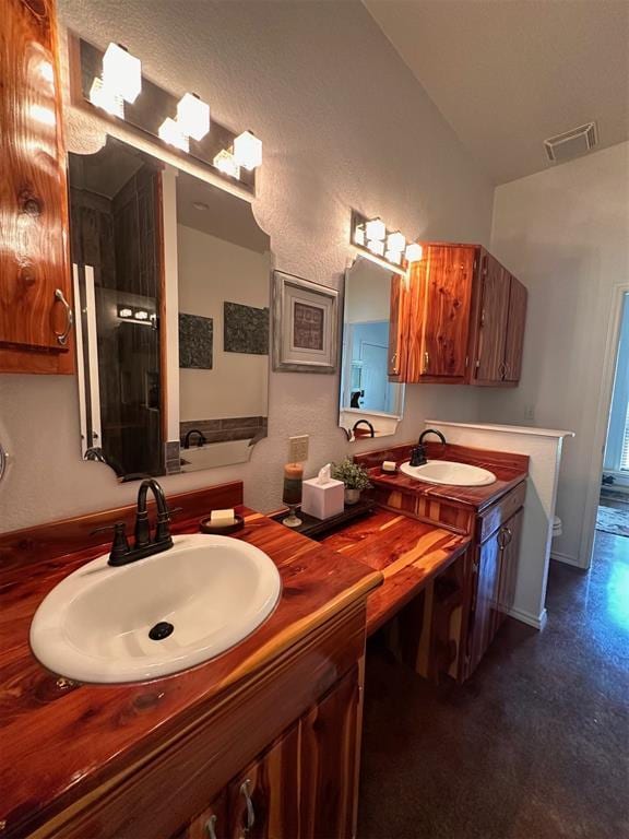 full bath with double vanity, visible vents, a sink, and lofted ceiling