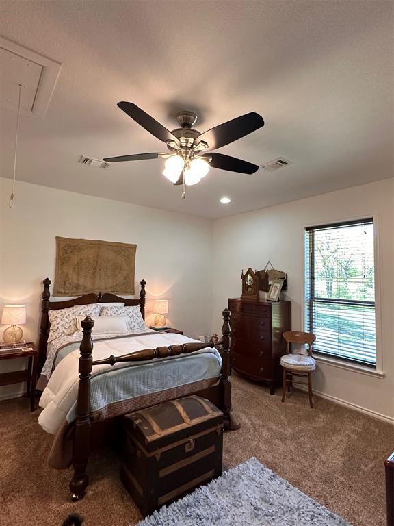 bedroom with carpet flooring, visible vents, attic access, and a ceiling fan