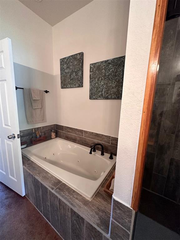full bathroom featuring a tile shower and a tub with jets