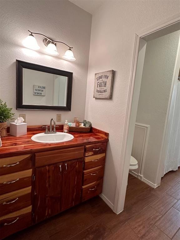 full bathroom with toilet, wood finished floors, vanity, and baseboards