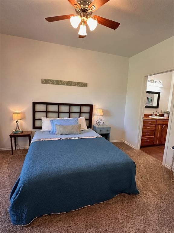 carpeted bedroom featuring a sink, a ceiling fan, baseboards, and ensuite bath