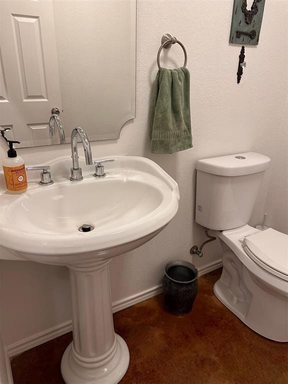 bathroom featuring a sink, toilet, and baseboards
