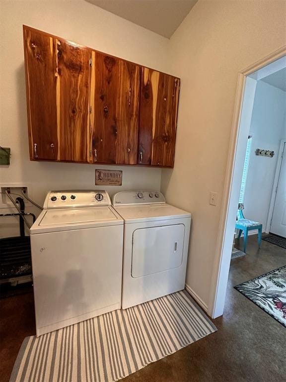 laundry area featuring washing machine and dryer, baseboards, and cabinet space
