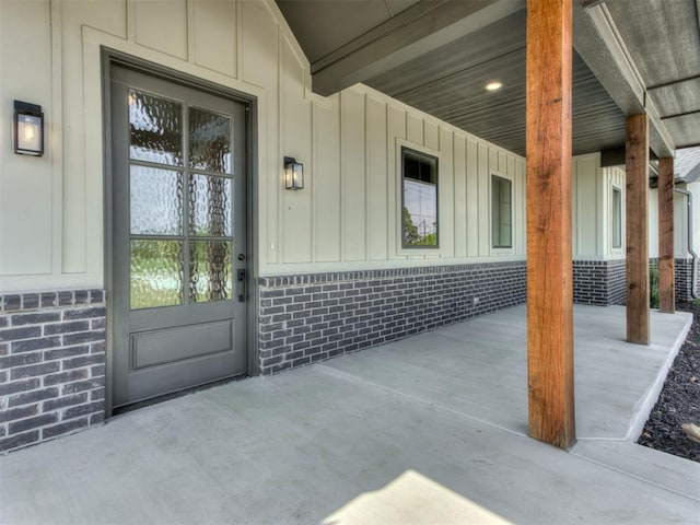 15528 NE 36th St, Choctaw, OK 73020 - view of exterior entry with board and batten siding, a porch, and brick siding