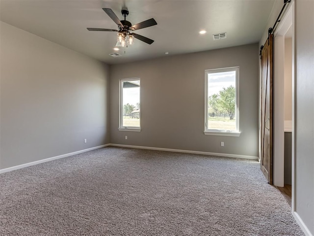 15528 NE 36th St, Choctaw, OK 73020 - empty room featuring a barn door, plenty of natural light, visible vents, and light carpet