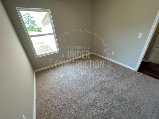 spare room featuring dark colored carpet and baseboards
