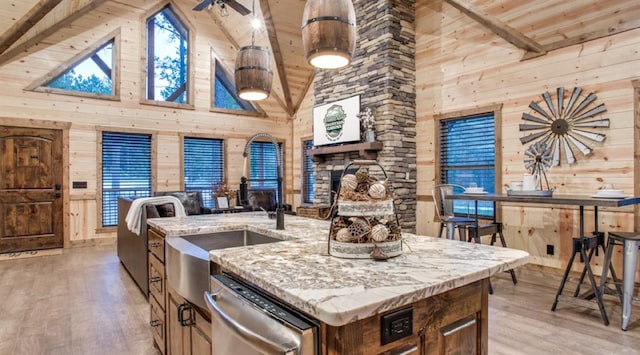 kitchen with light wood-style floors, wood ceiling, wood walls, stainless steel dishwasher, and high vaulted ceiling