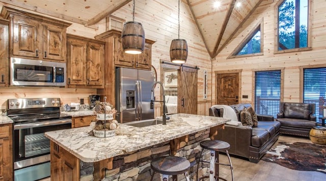kitchen featuring high vaulted ceiling, wooden walls, open floor plan, stainless steel appliances, and wooden ceiling