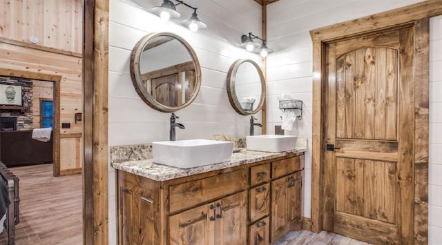 full bathroom featuring double vanity, wood finished floors, wood walls, and a sink
