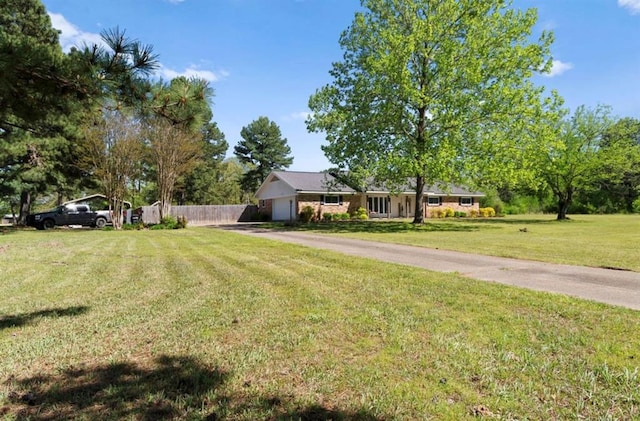 view of front facade featuring fence, driveway, a front yard, and a garage