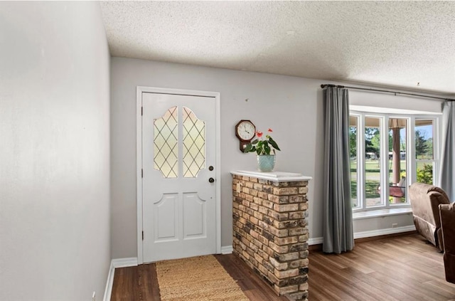 foyer with baseboards, wood finished floors, and a textured ceiling
