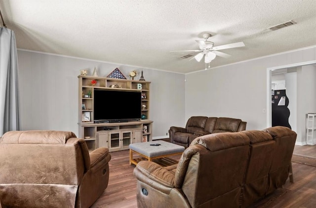 living area with crown molding, a ceiling fan, wood finished floors, and visible vents