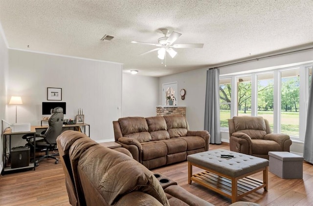 living room with light wood finished floors, plenty of natural light, a textured ceiling, and a ceiling fan