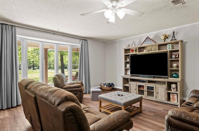 living room featuring a ceiling fan, wood finished floors, a textured ceiling, and visible vents